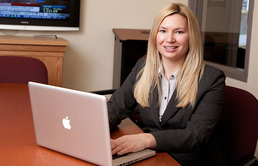 An alumnus of the Curry College Accounting Degree program sits at her laptop representing the Accounting Certificate program at Curry College