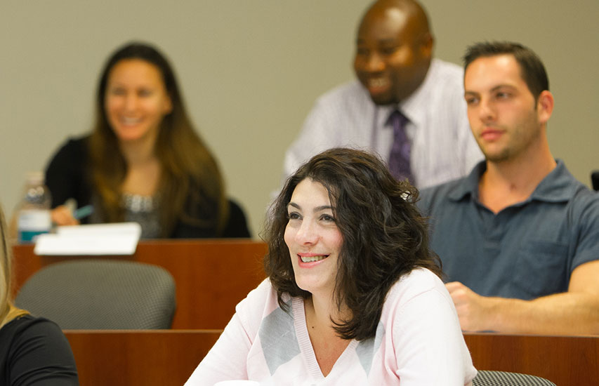 Students in class smiling while pursuing a Curry College MBA Degree