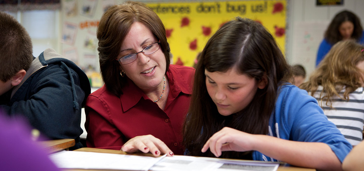 Curry College Post Master's Program is represented by a Curry College alumnus teaching an elementary school student