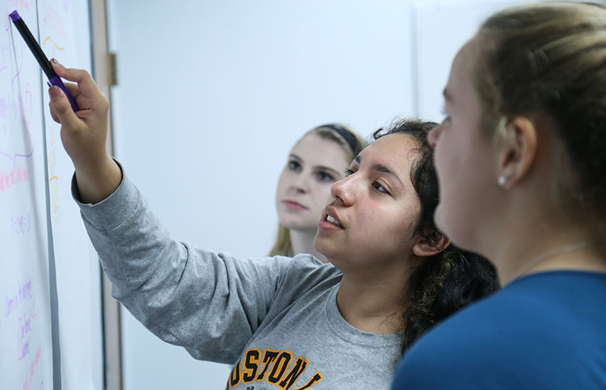 Students in class at the white board pursuing a 5th Year MBA degree at Curry College