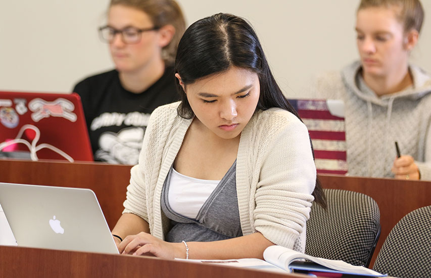 Student using a laptop in class, pursuing an Applied Computing Minor at Curry College