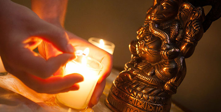 A student lighting a candle at Curry College, representing the Asian Studies Minor