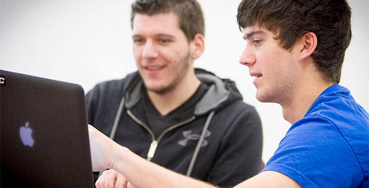 Students collaborate on a laptop while pursuing an Applied Computing minor at Curry College