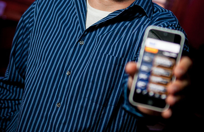 Alumnus hold up his cell phone to represent the Software Development degree at Curry College