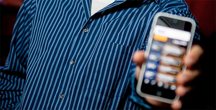 Alumnus hold up his cell phone to represent the Software Development degree at Curry College