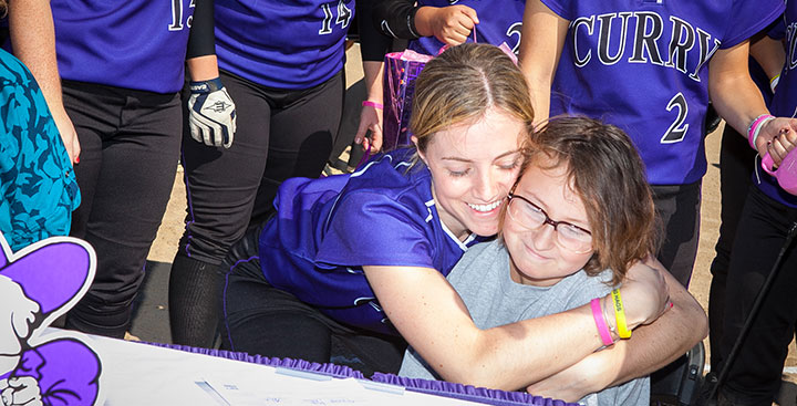Curry College student-athlete hugs a Team Impact patient
